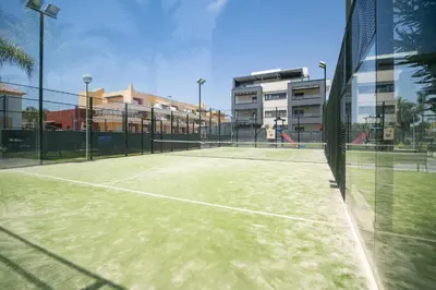 a tennis court in front of some buildings at Calma Beach Bajo de Guía in Sanlúcar de Barrameda