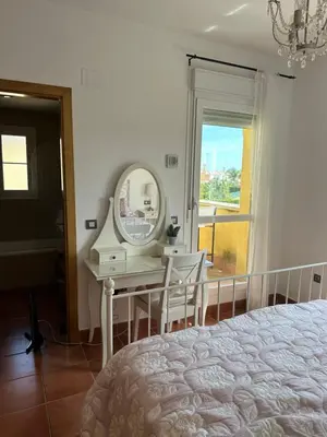 a bedroom with a mirror and a table with chairs at Villa Loma Cris y Javi in Cádiz