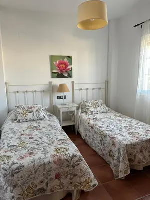 a bedroom with two beds and a table with a lamp at Villa Loma Cris y Javi in Cádiz