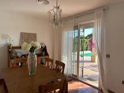 a dining room with a table and a vase of flowers at Villa Loma Cris y Javi in Cádiz