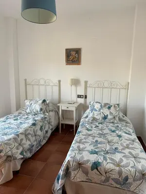 a bedroom with two beds and a table with a lamp at Villa Loma Cris y Javi in Cádiz