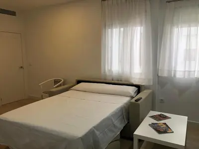 a bedroom with a bed and a table and a window at Cabildo Plaza 1 Sanlúcar de Barrameda in Sanlúcar de Barrameda