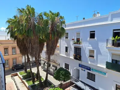 a white building with palm trees in front of it at Cabildo Plaza 1 Sanlúcar de Barrameda in Sanlúcar de Barrameda