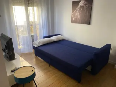 a blue bed in a room with a desk and a tv at Apartamento La Isla in San Fernando