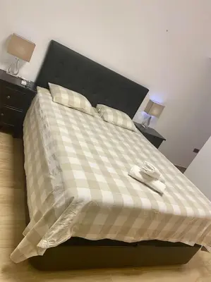 a bed with a checkered blanket and two pillows at Acogedora casa de invitados con piscina 1 in El Puerto de Santa María