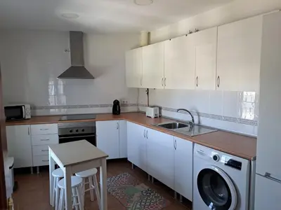 a kitchen with white cabinets and a washing machine at La Cuesta in Medina Sidonia
