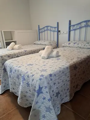 a room with three beds with blue and white sheets at La Cuesta in Medina Sidonia