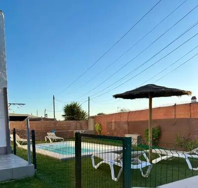 a patio with an umbrella and chairs and a pool at Ohana in Conil de la Frontera