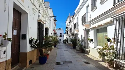 an alley in an old town with potted plants at fantástico apartamento chipiona in Chipiona