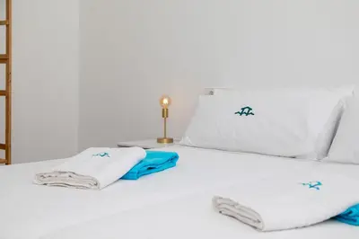 a white bed with white pillows and blue towels on it at Elena Sea Villa in Poblado de Sancti Petri
