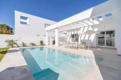 a swimming pool in front of a white house at Elena Sea Villa in Poblado de Sancti Petri