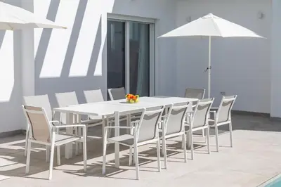 a white dining table and chairs with an umbrella at Elena Sea Villa in Poblado de Sancti Petri