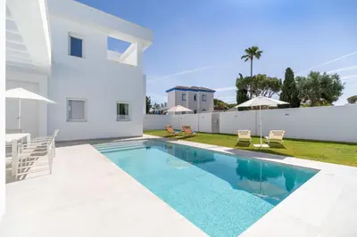 a swimming pool in the backyard of a white villa at Elena Sea Villa in Poblado de Sancti Petri