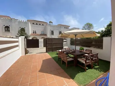 a patio with a table with an umbrella and chairs at Casa Playa la Jara in Sanlúcar de Barrameda