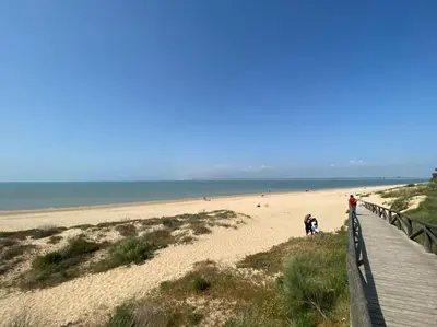 a boardwalk leading to a beach with people on it at Casa Playa la Jara in Sanlúcar de Barrameda