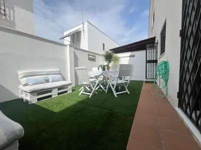 a patio with a table and chairs on a lawn at Casa Playa la Jara in Sanlúcar de Barrameda