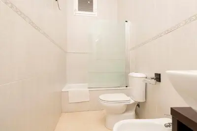 a white bathroom with a toilet and a sink at Carmen Viejo in Sanlúcar de Barrameda