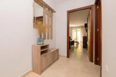 a hallway with white walls and a wooden cabinet and a mirror at Carmen Viejo in Sanlúcar de Barrameda