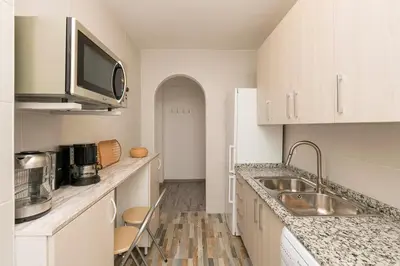 a white kitchen with a sink and a microwave at La Isleña in San Fernando