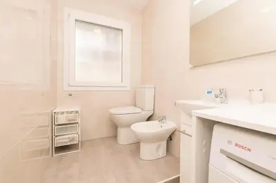 a white bathroom with a toilet and a sink at La Isleña in San Fernando
