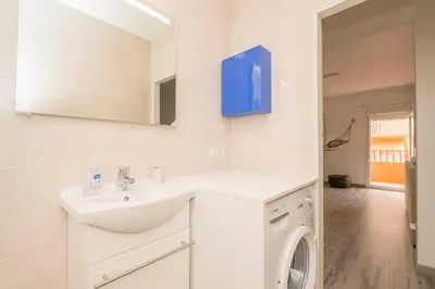 a white bathroom with a sink and a washing machine at La Isleña in San Fernando