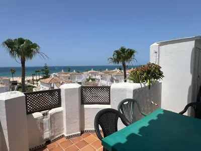 a balcony with a table and a view of the beach at La Barrosa in Novo Sancti Petri