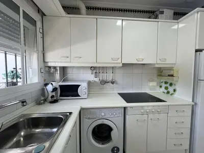 a white kitchen with a sink and a washing machine at La Barrosa in Novo Sancti Petri