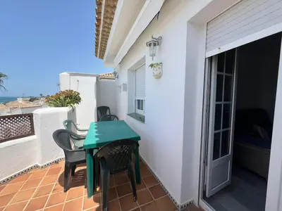 a small balcony with a green table and chairs at La Barrosa in Novo Sancti Petri