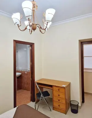 a bedroom with a desk and a chair and a chandelier at Roy's Cadiz Inn in Cádiz