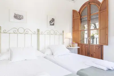 a white bedroom with two beds and a window at Apartamento con terraza en Playa de Regla. 6. in Chipiona