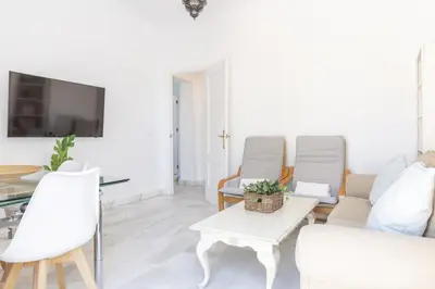 a living room with a couch and chairs and a tv at Apartamento con terraza en Playa de Regla. 6. in Chipiona