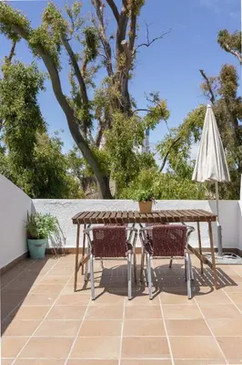 a wooden table with two chairs and an umbrella at Apartamento con terraza en Playa de Regla. 6. in Chipiona