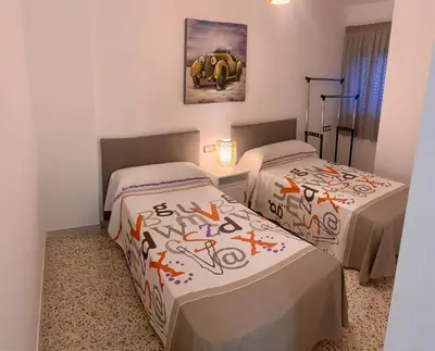 a room with two beds and a painting on the wall at Apartamento La Paz in Sanlúcar de Barrameda