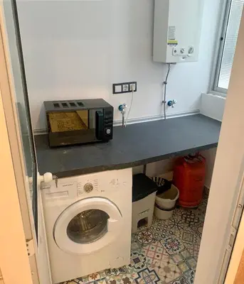 a kitchen with a microwave and a washing machine at Apartamento La Paz in Sanlúcar de Barrameda