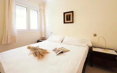 a bedroom with a white bed with a book on it at Summerlandrota La Caleta in Rota