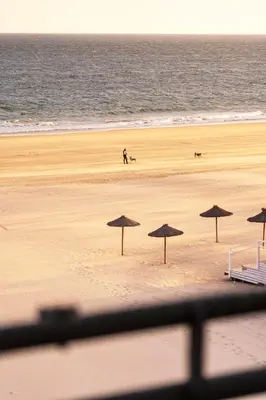 a person walking on a beach with umbrellas at Summerlandrota La Caleta in Rota