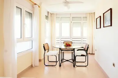 a dining room with a table and chairs and a window at Summerlandrota La Caleta in Rota