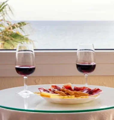 two glasses of red wine and a plate of fruit at Summerlandrota La Caleta in Rota