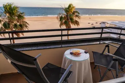 a table and chairs on a balcony overlooking the beach at Summerlandrota La Caleta in Rota