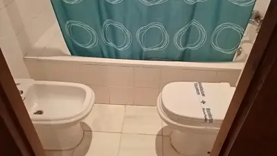 a bathroom with a toilet and a green shower curtain at Apartamentos Jasmund - Bungalow 119 in San Fernando