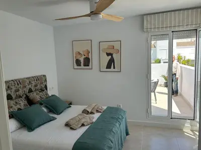 a large bed in a white room with a ceiling fan at Novo Sancti Petri in Cádiz