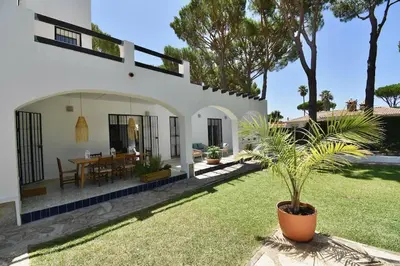 a house with a palm tree in the yard at Chici - Holiday Chiclana in Chiclana de la Frontera