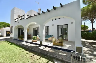 a white house with a patio and a yard at Chici - Holiday Chiclana in Chiclana de la Frontera