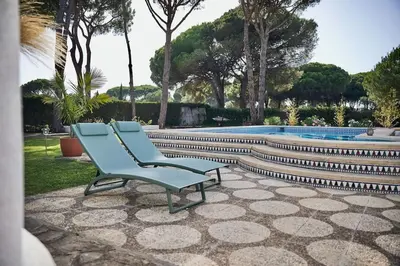 a blue chair sitting on a patio next to a swimming pool at Chici - Holiday Chiclana in Chiclana de la Frontera