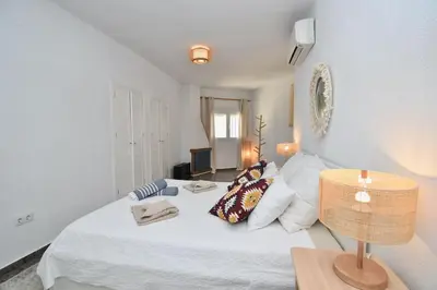 a bedroom with a white bed with a table and a lamp at Chici - Holiday Chiclana in Chiclana de la Frontera