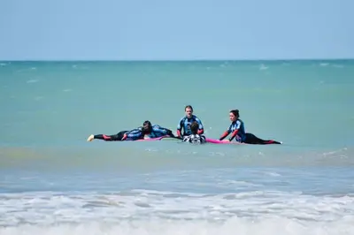 three people laying on a surfboard in the water at Disfruta Vacaciones Familiares Piso Frente al Mar in Cádiz