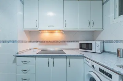 a kitchen with white cabinets and a microwave at Disfruta Vacaciones Familiares Piso Frente al Mar in Cádiz