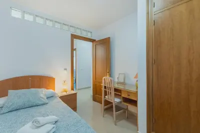 a bedroom with a bed and a desk with a chair at Disfruta Vacaciones Familiares Piso Frente al Mar in Cádiz