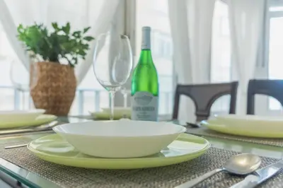 a table with a white bowl and a bottle of wine at Disfruta Vacaciones Familiares Piso Frente al Mar in Cádiz