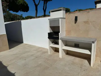 a patio with a white wall and a stove at Chalet con piscina in Chiclana de la Frontera